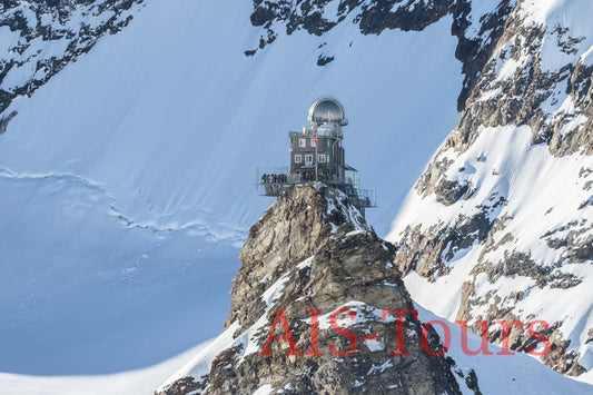 Вид на смотровую площадку на вершине заснеженной горной вершины в Швейцарских Альпах. Вершина Европы. View of an observation building atop a snowy mountain peak in the Swiss Alps.